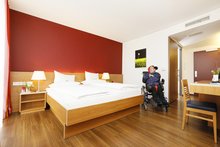 Gast im Rollstuhl in einem rollstuhlgerechten Zimmer im barrierefreien Hotel Franz in Essen