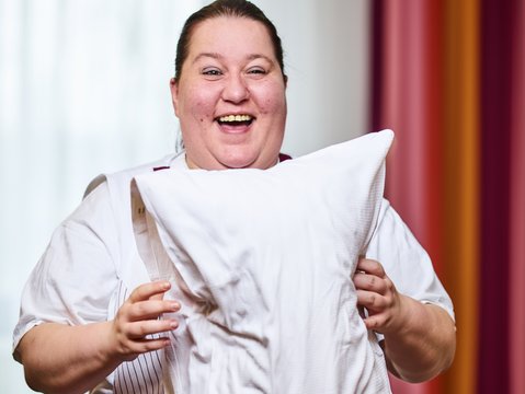 Mitarbeiterin des Housekeepings im Hotel Franz in Essen schüttelt das Kopfkissen auf.